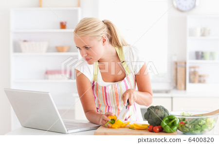 Woman using a laptop to cook 6400820
