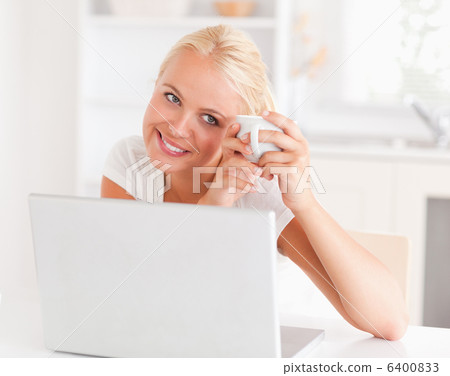 Woman having a coffee while using her laptop Woman having a coffee while using her laptop 6400833