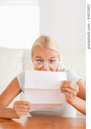Woman looking at a letter in disbelief Woman looking at a letter in disbelief 6401001