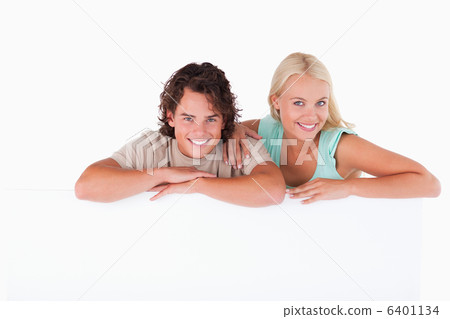 Cute couple leaning on a whiteboard 6401134