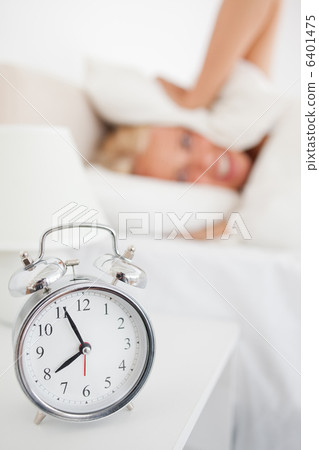 Portrait of a woman hidding her head in a pillow while the alarm Portrait of a woman hidding her head in a pillow while the alarm 6401475