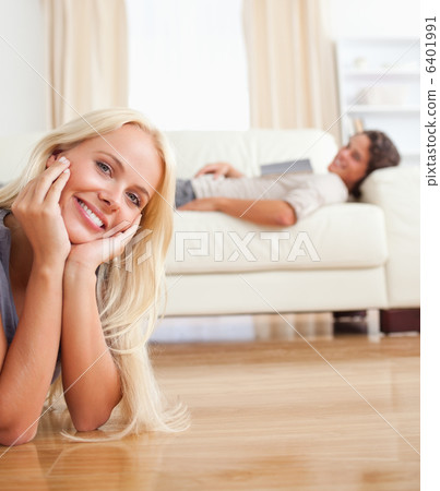 Portrait of a woman lying on the floor while her fiance is with 6401991