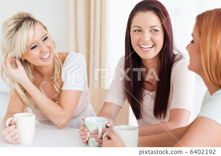 Joyful young Women sitting at a table with cups 6402192