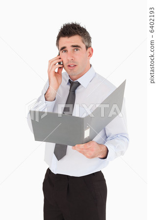 Portrait of a man making a phone call while holding a binder Portrait of a man making a phone call while holding a binder 6402193