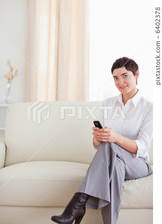 Charming Woman sitting on a sofa with a phone Charming Woman sitting on a sofa with a phone 6402378