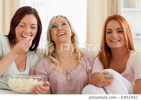 Charming women lounging on a sofa watching a movie 6402492
