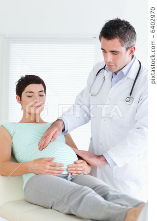 Doctor examining the belly of a pregnant woman 6402970