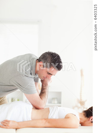 Chiropractor doing accupressure on a womans back 6403325