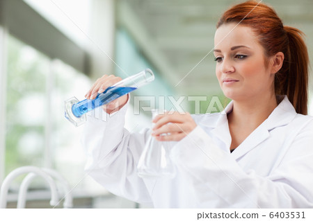 Scientist pouring liquid in an Erlenmeyer flask Scientist pouring liquid in an Erlenmeyer flask 6403531