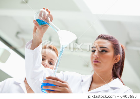 Scientist emptying a flask into another one 6403683