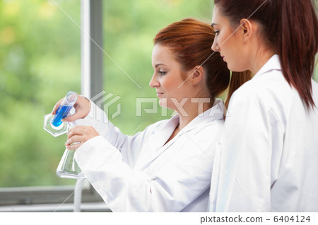 Young scientists pouring liquid in an Erlenmeyer flask Young scientists pouring liquid in an Erlenmeyer flask 6404124