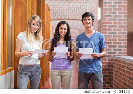 Smiling students holding a piece of paper Smiling students holding a piece of paper 6404133