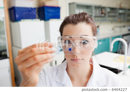 Cute science student looking at a microscope slide 6404227