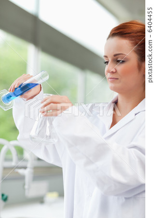 Portrait of a science student pouring liquid in an Erlenmeyer fl Portrait of a science student pouring liquid in an Erlenmeyer fl 6404455