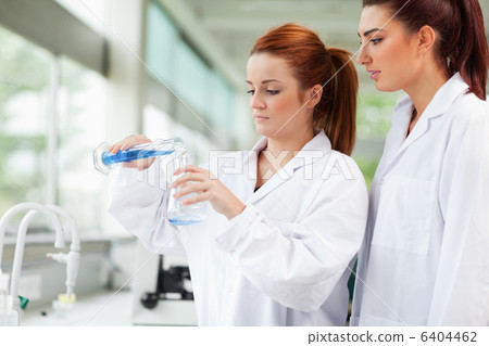 Cute scientists pouring liquid in an Erlenmeyer flask Cute scientists pouring liquid in an Erlenmeyer flask 6404462