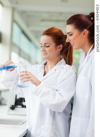 Portrait of scientists pouring liquid in an Erlenmeyer flask Portrait of scientists pouring liquid in an Erlenmeyer flask 6404463