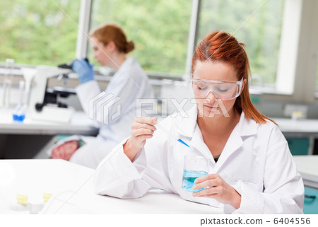 Scientist dropping blue liquid in a beaker 6404556