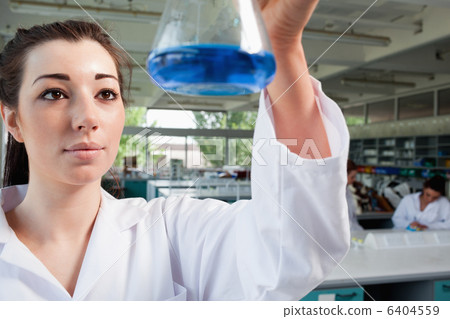 Science student looking at a blue liquid 6404559