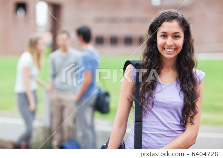 Cute student posing while his classmates are talking 6404728