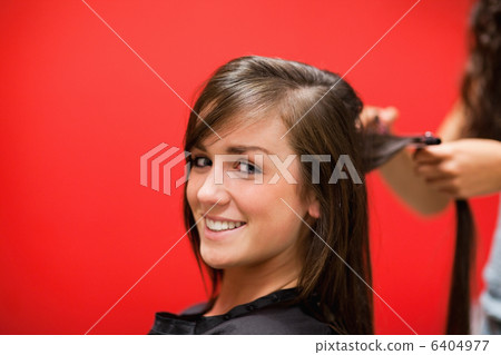 Young woman having her hair straightened 6404977