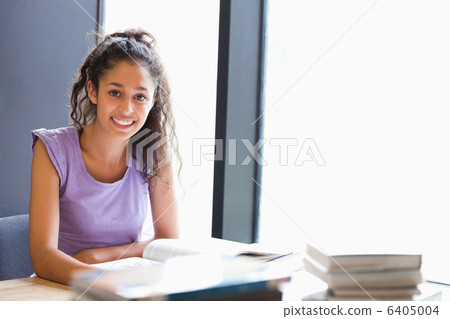 Smiling student sitting with a book 6405004