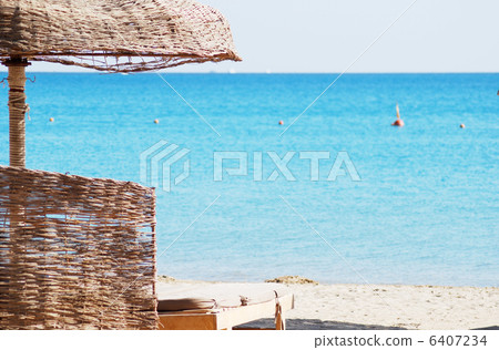 empty beach chair with straw sunshade at the sea 6407234