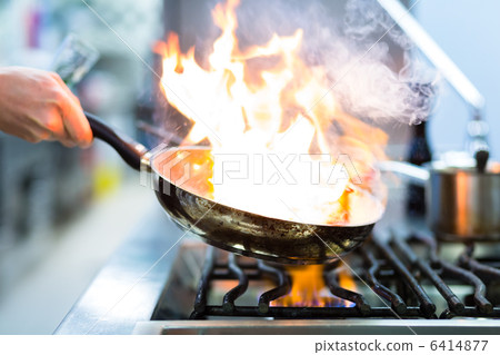 Chef in restaurant kitchen at stove with pan Chef in restaurant kitchen at stove with pan 6414877