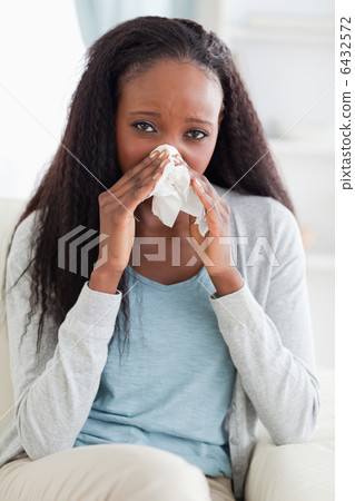 Close up of woman on couch blowing her nose Close up of woman on couch blowing her nose 6432572