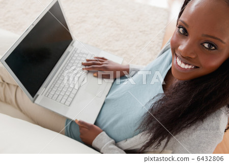 Smiling woman with laptop on sofa 6432806
