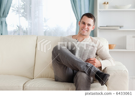 Smiling man reading a newspaper 6433061