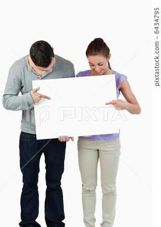 Young couple pointing at banner they are holding Young couple pointing at banner they are holding 6434795