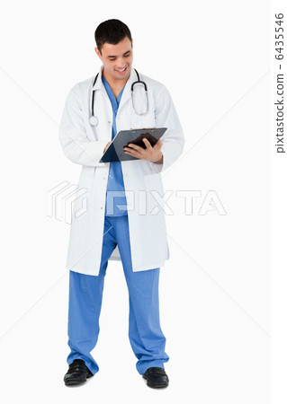 Portrait of a young doctor writing on a clipboard Portrait of a young doctor writing on a clipboard 6435546