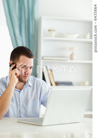 Businessman on his cellphone while working on his laptop 6435664