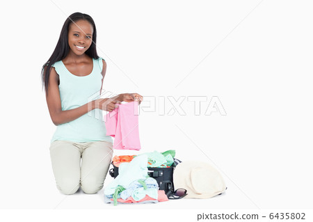 Smiling young woman packing her trunk 6435802