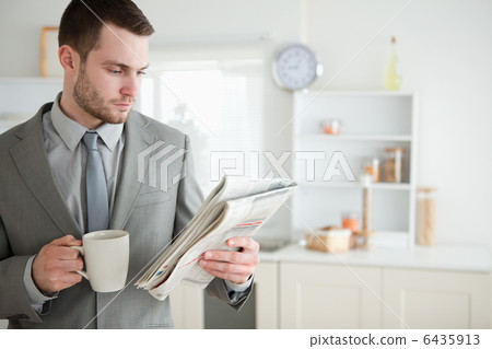 Businessman drinking coffee while reading the news 6435913