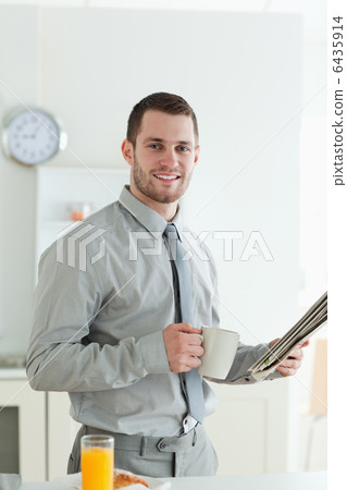 Portrait of a smiling businessman reading the news while having Portrait of a smiling businessman reading the news while having 6435914