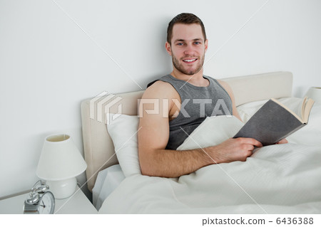 Smiling man reading a novel Smiling man reading a novel 6436388