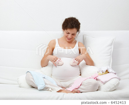 Beautiful pregnant woman choosing babys clothes 6452413