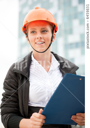 Young architect-woman wearing a protective helmet standing on th 6459831