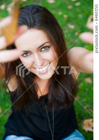 Portrait of smiling young girl sitting on grass in the forest an 6460350
