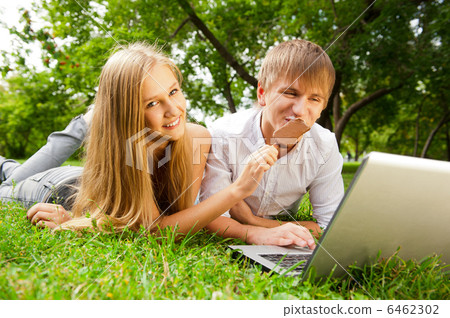 College students using laptop on campus lawn College students using laptop on campus lawn 6462302