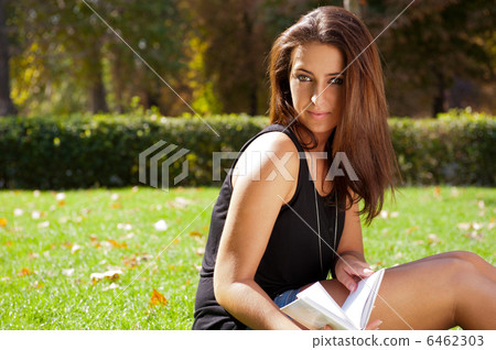 Portrait of a beautiful young female student sitting outdoor at Portrait of a beautiful young female student sitting outdoor at 6462303