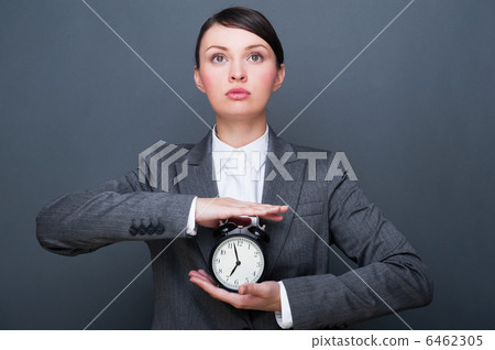 Bright picture of woman holding alarm clock against grey backgro Bright picture of woman holding alarm clock against grey backgro 6462305