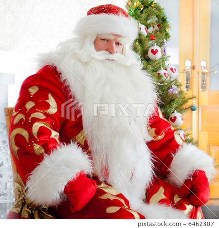 Santa sitting at the Christmas tree, fireplace and looking at ca Santa sitting at the Christmas tree, fireplace and looking at ca 6462307