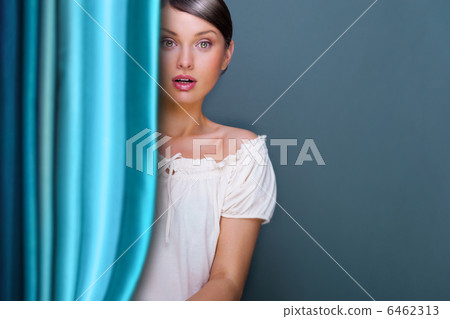 Closeup of young, pretty woman standing near curtain and holding 6462313