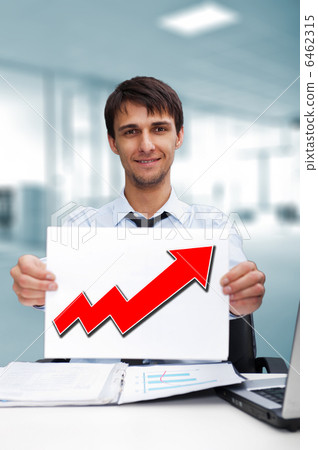 Attractive man in business suit with sign of up graph sitting at Attractive man in business suit with sign of up graph sitting at 6462315