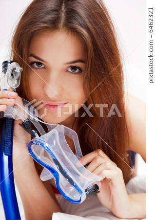 Young woman in bed holding diving mask and dreaming about vacati 6462321