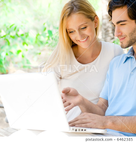 Young couple working on laptop and smiling while sitting relaxed 6462385