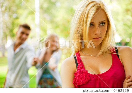 Upset teenage girl being jeered by group of the other young peop 6462529