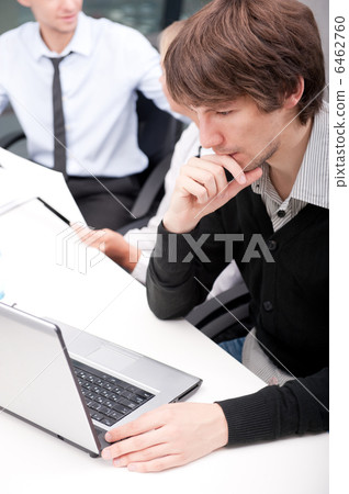 Friendly executive sitting in front of laptop Friendly executive sitting in front of laptop 6462760